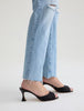Person wearing light blue jeans and black high-heeled sandals on a white background