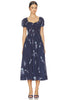 A woman modeling a navy blue midi dress with a white floral print, featuring a sweetheart neckline, puffed short sleeves, and a gathered waist, set against a plain white background.