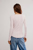 Person wearing a light pink long-sleeve top and blue jeans on a plain background