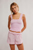 Woman wearing a pink textured top and shorts set against a plain background